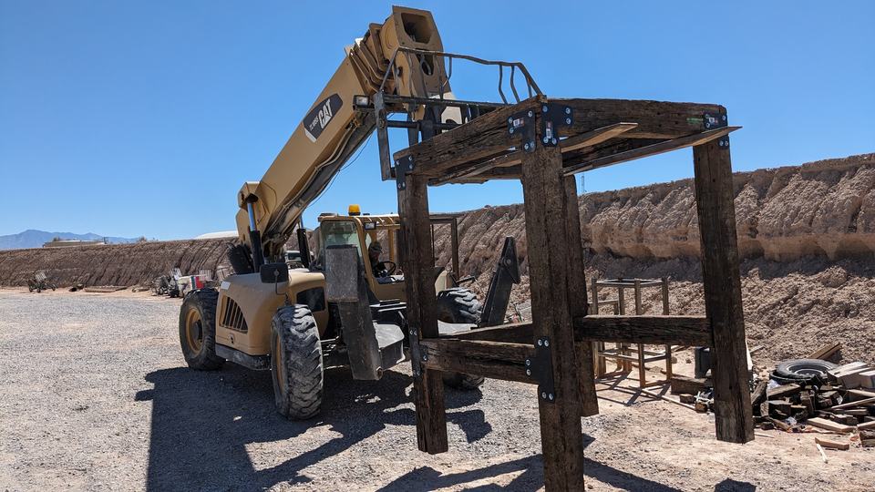 A telehandler setting a heavy timber station frame